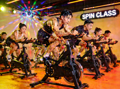 动感单车课程中，学员跟随音乐节奏奋力骑行的活力画面